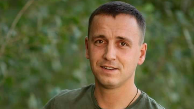 Олег Шульга у військовій формі усміхається на фоні зелені